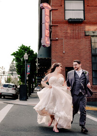 Wedding at the Hood River Hotel where bride and groom are running across the street in front of the hotel in Hood River Oregon.