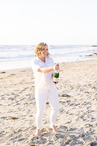 Lis Best popping a bottle of champagne on the beach