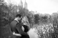 Central park engagement photos, Deborah Zoe Photography. A couple embrace near water's edge in Central Park.
