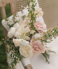 soft summer floral bouquet on birch bench with linen. pink and white roses.