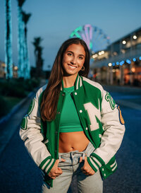 Senior portrait at The Wharf in Orange Beach, Alabama — wearing a Millry letterman jacket with
the Ferris wheel in the background.