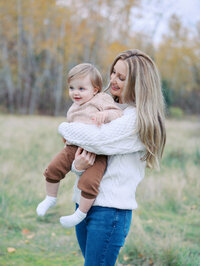 Mom spinning her baby boy son in a field at Magnuson park in Seattle