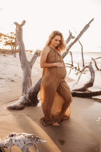 Folly Beach Maternity Photographer -- Pregnant woman poses for Maternity Photos at the Lighthouse Inlet Heritage Preserve on Folly Beach with iconic views of the Morris Island Lighthouse in the distance.