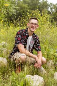 Boy in grass posing for high school senior photography in Shelby Township MI