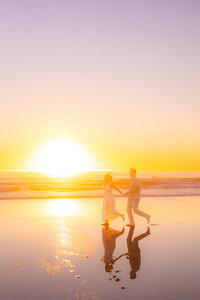 sunset beach couple running across sand barefoot in santa cruz.