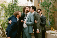 Groom with groomsmen sharing playful moment outdoors at wedding