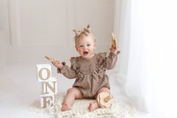 A one-year-old little girl celebrates turning a year old at her studio Cakesmash session near Mankato, Minnesota with Jennifer Brandes Photography.