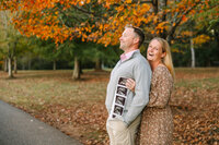 Couple laughing and hugging as they hold ultrasound for expecting baby