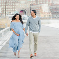 Laughing pregnant woman walking while holding hands with smiling husband