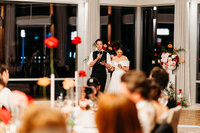 Bride and Groom across a room while they give a speech to their loved ones at their wedding