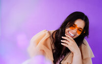 Singer-songwriter laughing in orange glasses during a colorful personality-driven brand photoshoot