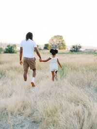 Dad and daughter walking in a grassy meadow in Discovery Park