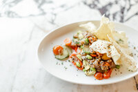 Close up photo of a beautiful menu item from Sip and Savor of a salad sitting on a marble table.