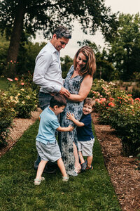 Family of four hugging and laughing in rose garden at Brandywine Park.  Photo taken by Delaware family photographer, Kristi