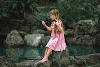 Child sitting near water holding butterfly in New Bern NC