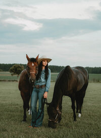 Senior portrait at Triple T Farms in Fruitdale, Alabama — standing beside two horses as one
faces the camera and the other grazes.