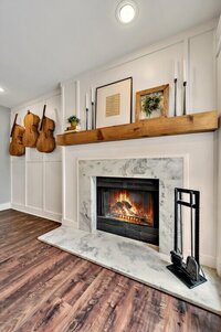 Marble fireplace and open beam mantle in this three-bedroom, two-bathroom vacation rental home featured on Chip and Joanna Gaines' Fixer Upper located in downtown Waco, TX.