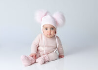 little-girl-in-light-pink-hat-with-fluffy-pom-poms
