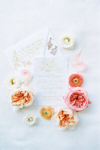 wedding invitations surrounded by pink and red flowers