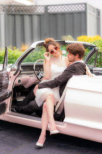 bride with sunglasses sitting on groom in classic car at hollins house in santa cruz