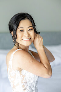 beautiful Asian bride putting on her earrings in a hotel room