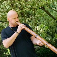 Joseph Carringer of Didge therapy playing the didgeridoo in the forest. Joseph offers sessions in sound healing with didgeridoo at Thrive on Health.