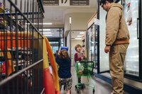 A dad and his children grocery shopping in the ice cream aisle