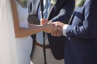 Close up detail of bride and groom holding hands during wedding ceremony.