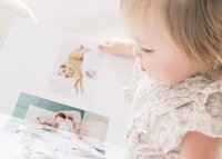 baby girl looking at photo album from her newborn session
