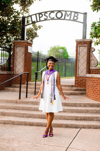 College grad standing at the bottom of the stairs by the Lipscomb arc at the edge of campus
