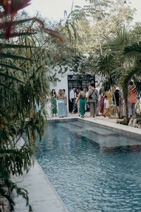 Poolside destination wedding with guests enjoying cocktail hour wearing tropical colors