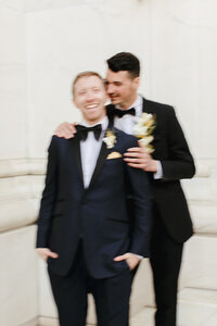 Motion blurs two grooms as they embrace in black tie attire. Photo by Jordan Katz.