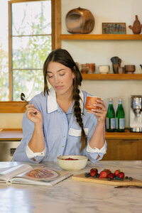 Woman with breakfast and coffee at a marble kitchen island, nutrition vertical