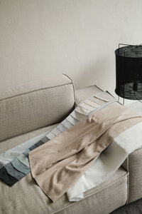 sitting area with grey fabric chair and white boucle pillow and white circular side table with modern white sculptural vase and  white roses