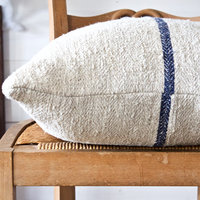 Cream grain sack pillow with blue stripe, on top of chair