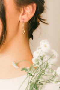 Editorial-style product photography of delicate jewelry worn to show scale, movement, and refined detail