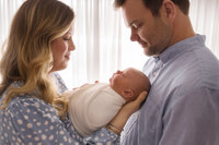 Newborn Pictures in Charleston - New Parents embrace their infant during Newborn Pictures at Holy City Babies Newborn Photography Studio in Charleston, SC.