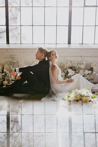 bride and groom sit in front of window