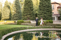 A Newly Married Couple Walks on the Grass in front of the Broadmoor's Main Hotel