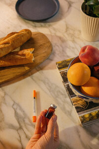 Overhead still life on a marble counter with fresh fruit, bread, and Mochi product