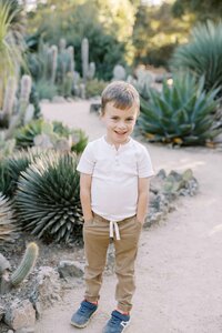 little boy with hands in pockets and smiling