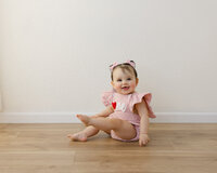 She wore her heart on her romper and her joy in every smile. Captured by Yucaipa cake smash photographer Kaitlyn Dawn Photography.