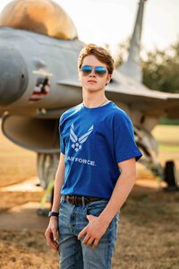 Senior posing in an air force shirt on the grounds of Mobile Battleship Parkway.