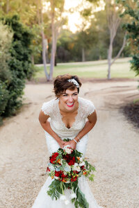 Bride laughing while holding bouquet outdoors