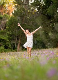 Professional photography by Nature's Child Photography: Senior dances through a soft meadow of purple wildflowers in Palatka, golden light and open space creating a dreamy, free-spirited senior.