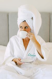 Guest in an L'Auberge Del Mar robe with morning coffee after a spa treatment