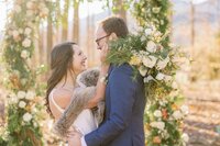 Bride and groom framed by lush greenery wedding arbor designed by Flowergirl Cville, Charlottesville florist | Photo by Xiaoqi Li Photography
