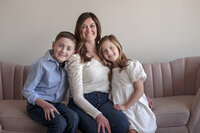 A mom sitting on a couch smiling with two kids.