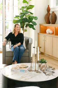 Personal brand photography of an interior designer seated in a styled living room, photographed for brand storytelling