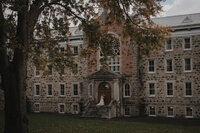 Vue cinématographique d’un couple de mariés sur le perron de l’Abbaye d’Oka, mis en scène dans une composition architecturale capturée par Jeff Gagnon photographe.